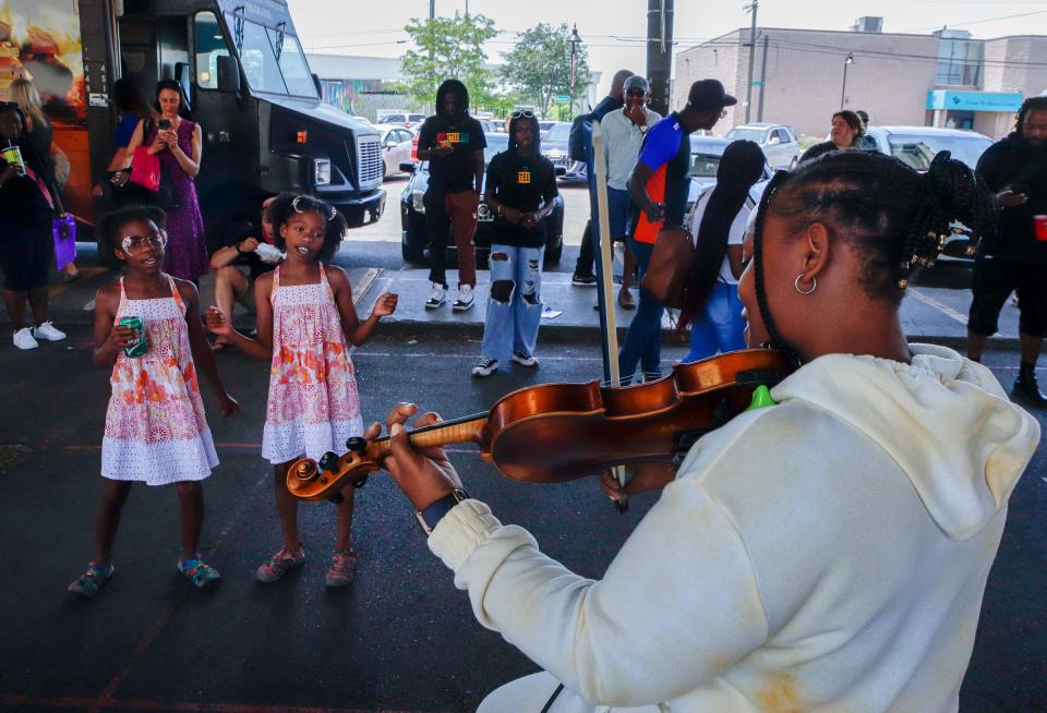 From Left, Twins, Emi LaRosa, 9, and Gemma LaRosa, 9, dance to the violin music played by Kym Brady, 20, at the Juneteenth Fest at the Eastern Market in Detroit on Sunday, June 19, 2022. 