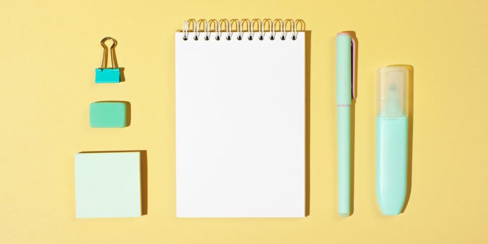 back to school quotes  organized flat lay of notepad, writing utensils, sticky notes and binder clip