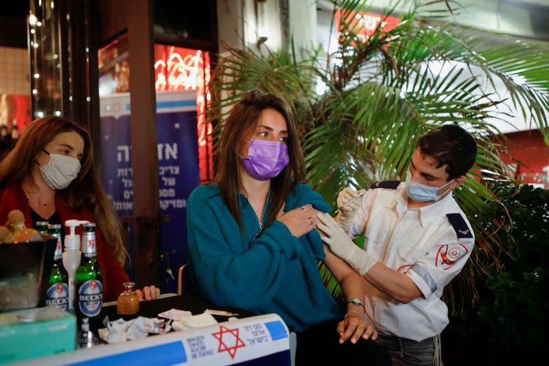 A woman receives a vaccination against the coronavirus disease (COVID-19) as part of a Tel Aviv municipality initiative offering a free drink at a bar to residents getting the shot, in Tel Aviv