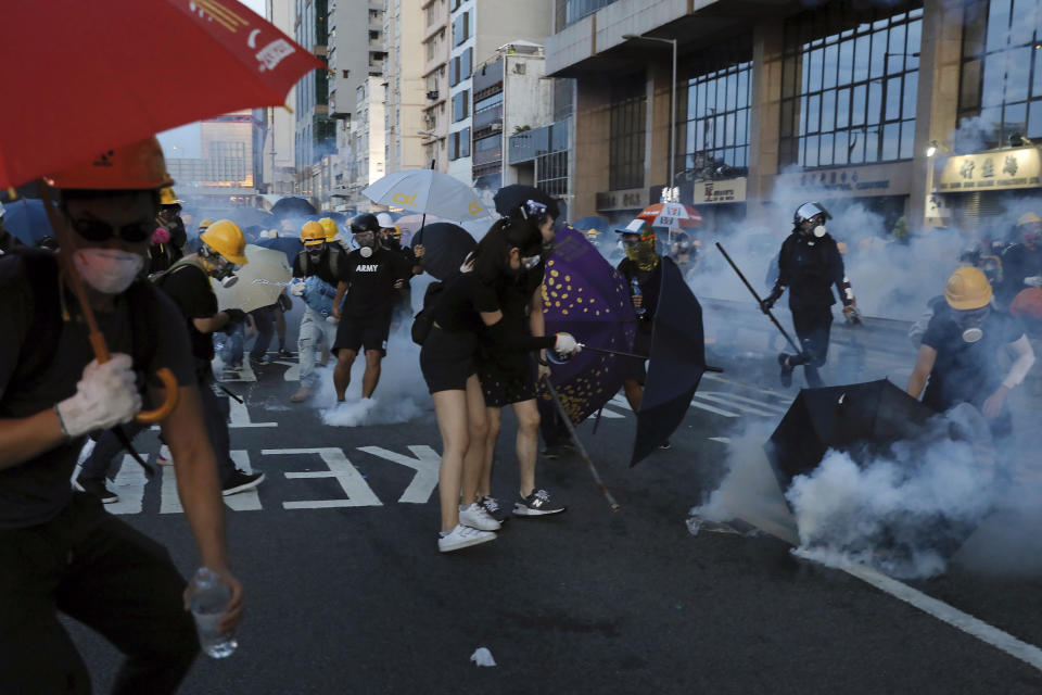 Protesters try to avoid tear gas as they face off with riot policemen on a streets in Hong Kong, Sunday, July 28, 2019. Police launched tear gas at protesters in Hong Kong on Sunday for the second night in a row in another escalation of weeks-long anti-government and pro-democracy protests in the semi-autonomous Chinese territory. (AP Photo/Vincent Yu)