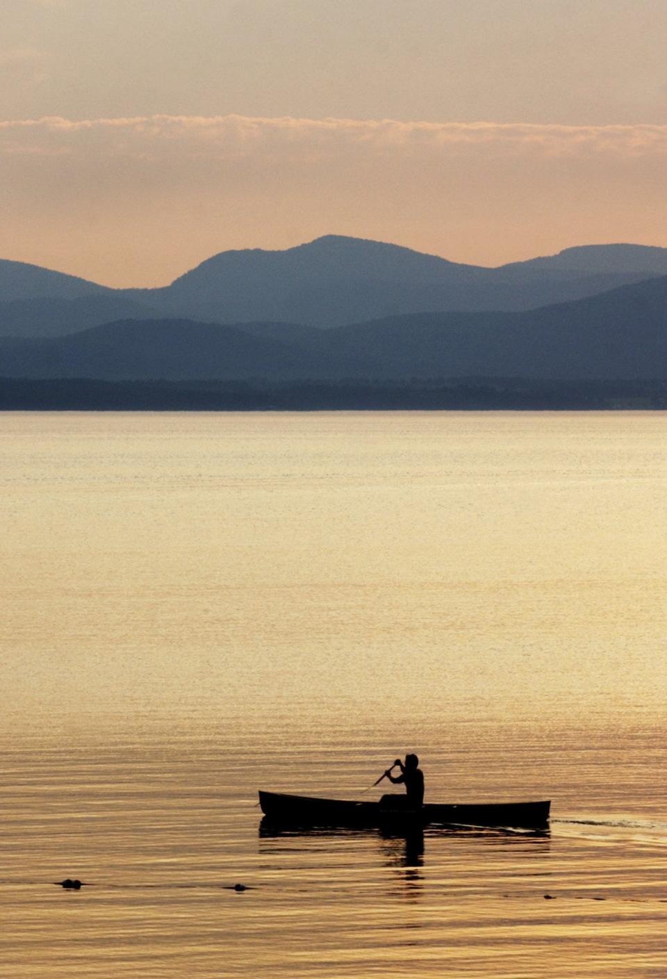 A canoeist paddles along the shoreline of Lake Champlain near the Shelburne town beach at sunset in this 2003 Free Press file photo.