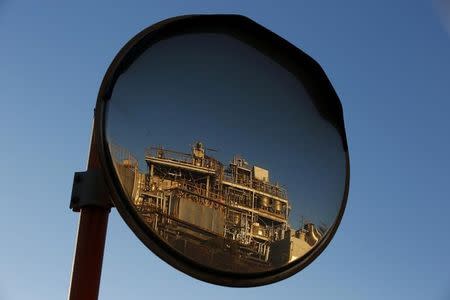 A petro-industrial factory is reflected in a traffic mirror in Kawasaki near Tokyo December 18, 2014. REUTERS/Thomas Peter/Files