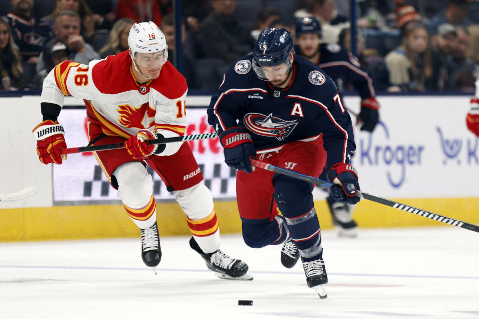 Columbus Blue Jackets forward Sean Kuraly, right, chases the puck in front of Calgary Flames defenseman Nikita Zadorov during the second period of an NHL hockey game in Columbus, Ohio, Friday, Oct. 20, 2023. (AP Photo/Paul Vernon)