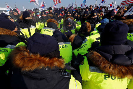 Police try to extinguish a fire after demonstrators burnt portraits of North Korean leader Kim Jong Un during an anti-North Korea protest before the opening ceremony for the Pyeongchang 2018 Winter Olympics in Pyeongchang, South Korea, February 9, 2018. REUTERS/Edgar Su