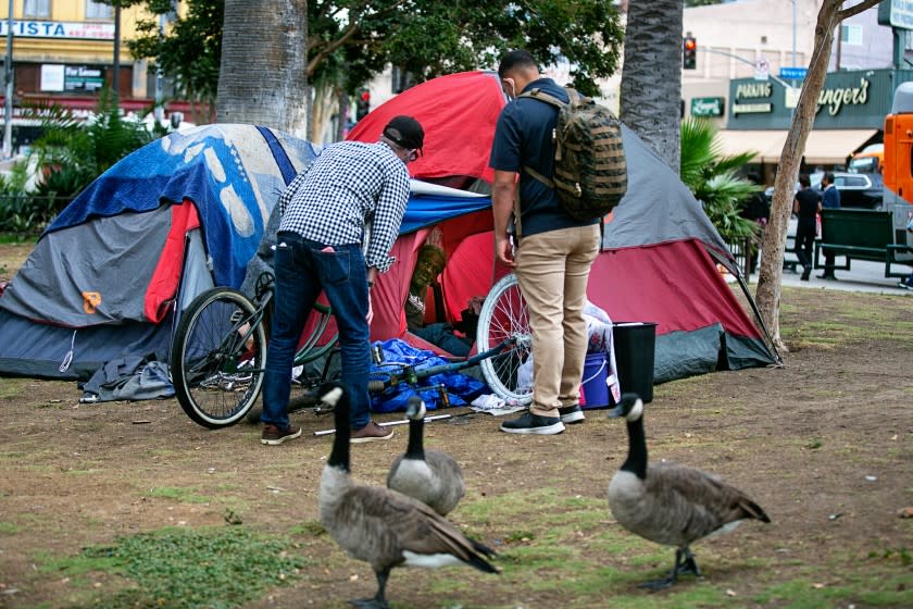 LOS ANGELES, CA - OCTOBER 08: Outreach workers begin the process of connecting an unhoused man in MacArthur Park with housing and other services before the park is cleared and closed for renovations on Friday, Oct. 8, 2021 in Los Angeles, CA. (Jason Armond / Los Angeles Times)