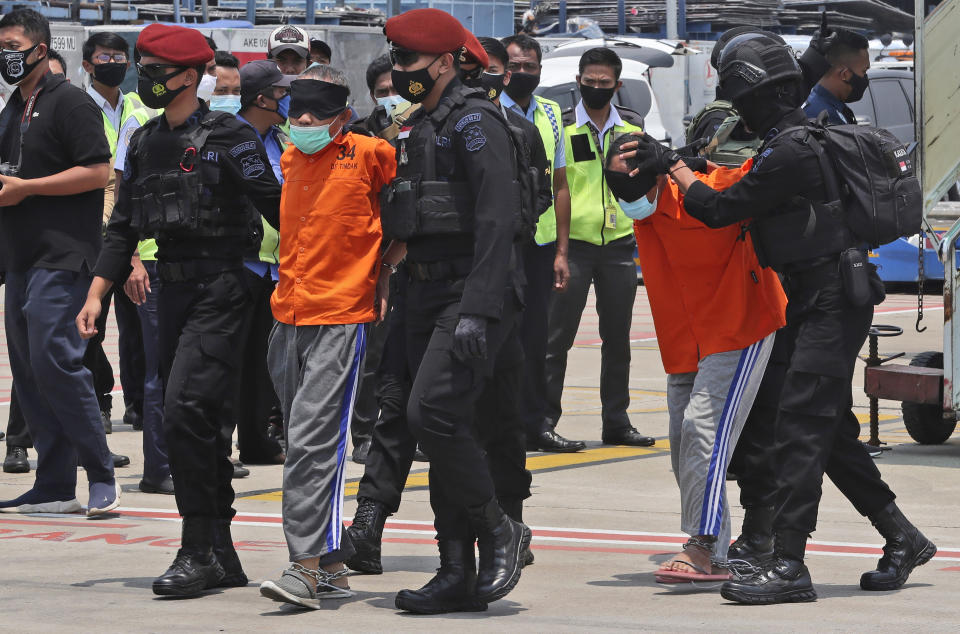 Police escort suspected militants upon arrival at the Soekarno-Hatta International Airport in Tangerang, Indonesia, Thursday, March 18, 2021. Indonesian authorities on Thursday transferred suspected militants arrested in raids in the last few weeks, from East Java to the capital city for further questioning. The militants are believed to be connected to linked to the al-Qaida-linked Jemaah Islamiyah extremist group. (AP Photo/Achmad Ibrahim)