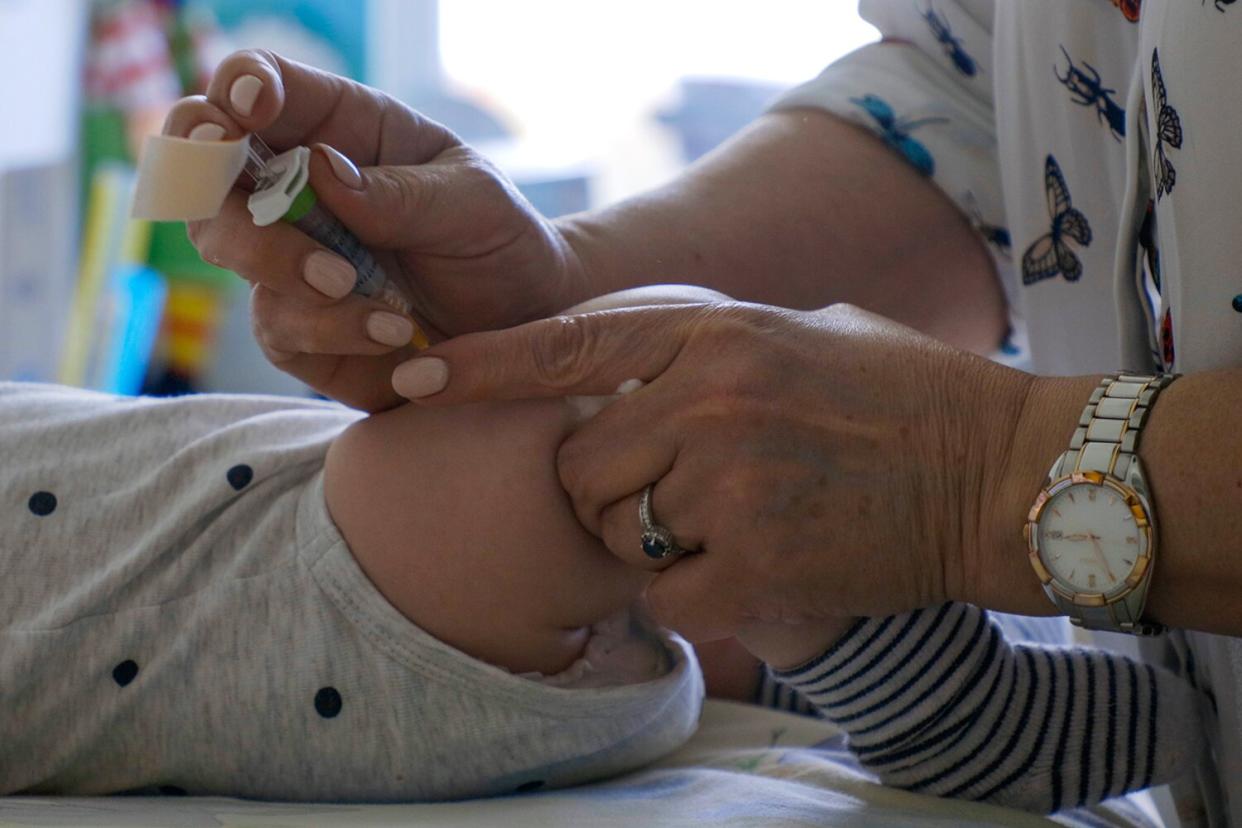 Paediatrician doctor preparing coronavirus vaccination and giving the vaccine to a small baby.