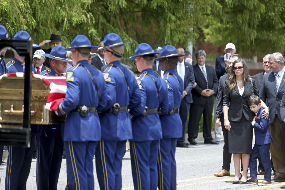 Edwin Edwards' wife Trina and son Eli, 7, watch as the flag-draped casket of the former Louisiana Governor arrives at the Old State Capitol building following a processional through the streets of Baton Rouge, La., Sunday, July 18, 2021. The processional featuring a law enforcement motorcade as well as the Southern University Marching Band and ended at the Old State Capital building where a private funeral service was held. The colorful and controversial four-term governor died of a respiratory illness on Monday, July 12th at the age of 93. (AP Photo/Michael DeMocker)