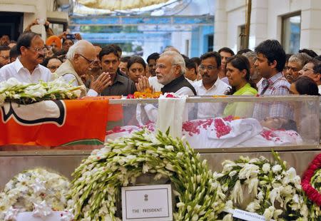 Prime Minister Narendra Modi (C) greets L.K. Advani, senior leader of Bharatiya Janata Party (BJP), next to the casket of Rural Development Minister Gopinath Munde at the party headquarters in New Delhi June 3, 2014. REUTERS/Anindito Mukherjee