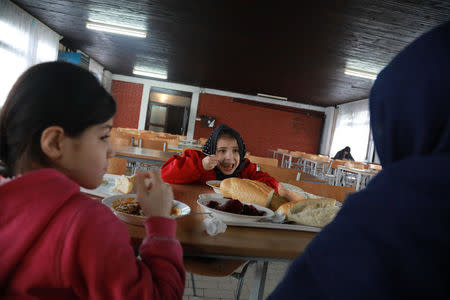 Sonya, 8, daughter of Afghan refugee Najibullah, and her sister, have lunch at the camp for refugees and migrants in the Belgrade suburb of Krnjaca, Serbia, January 16, 2018. Picture taken January 16, 2018 REUTERS/Djordje Kojadinovic