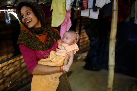 Noor Kayes, 18, smiles as she holds her 26-day-old unnamed daughter at their home in Kutupalang unregistered refugee camp in Cox’s Bazar, Bangladesh, February 9, 2017. REUTERS/Mohammad Ponir Hossain