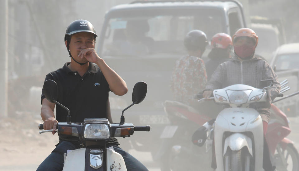 A man covers his nose as he drives through an air polluted street in Hanoi, Vietnam October 1, 2019. REUTERS/Kham