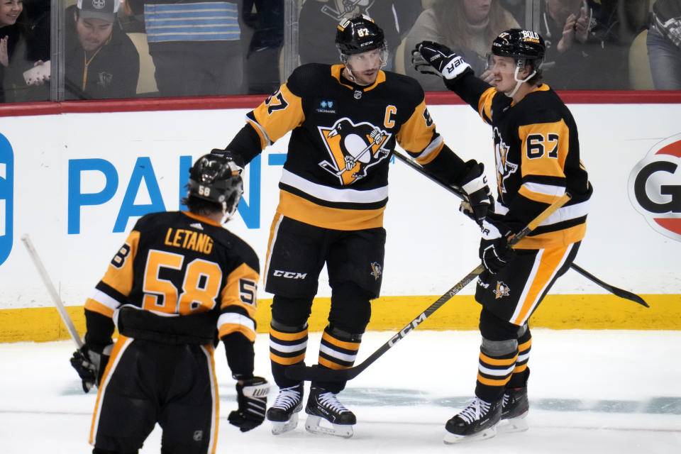 Pittsburgh Penguins' Sidney Crosby celebrates his goal with Rickard Rakell (67) during the first period of an NHL hockey game against the San Jose Sharks in Pittsburgh, Saturday, Jan. 28, 2023. (AP Photo/Gene J. Puskar)