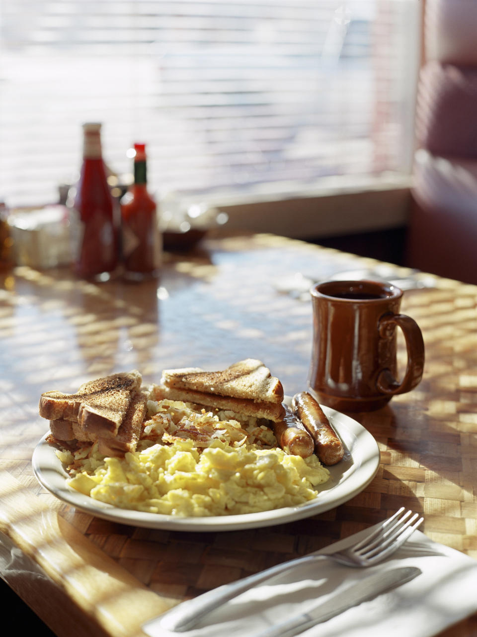 Scrambled eggs, sausages, hash brown, toast and coffee at a diner