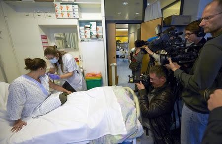 A nurse prepares a syringe containing an experimental Ebola virus vaccine next to a volunteer called Trina Helderman (L) during a media visit at the Lausanne University Hospital (CHUV) in Lausanne November 4, 2014. REUTERS/Denis Balibouse