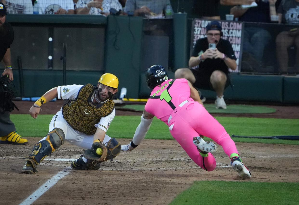 Jake Skole of the Party Animals, right, slides safely into home plate ahead of the tag by Savannah Bananas catcher Bill Leroy during a baseball game on Friday, Aug. 25, 2023, at Principal Park in Des Moines.