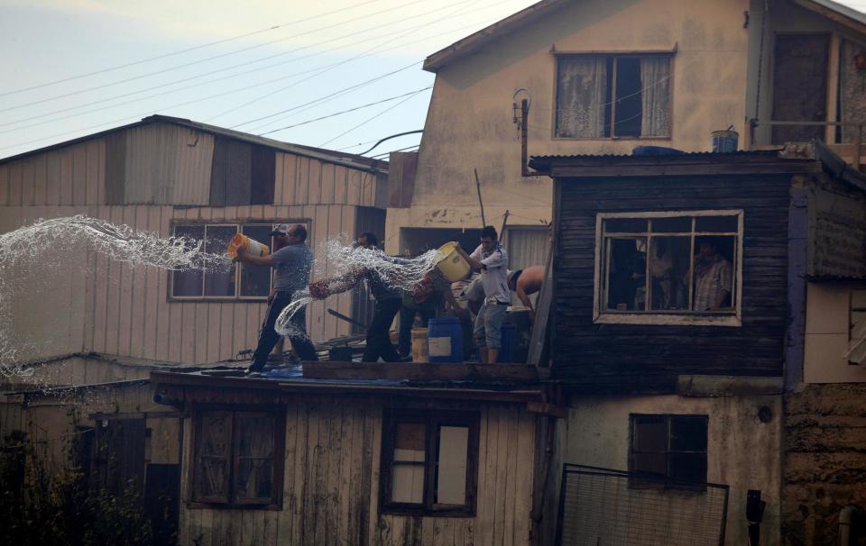 Residents throw water on a fire (not pictured) at the location where a forest fire burned several neighbourhoods in the hills in Valparaiso city, northwest of Santiago, April 13, 2014. At least 11 people were killed and 500 houses destroyed over the weekend by the fire that devastated parts of the Chilean port city of Valparaiso, as authorities evacuated thousands and sent in aircraft to battle the blaze. REUTERS/Cristobal Saavedra (CHILE - Tags: SOCIETY ENVIRONMENT DISASTER)