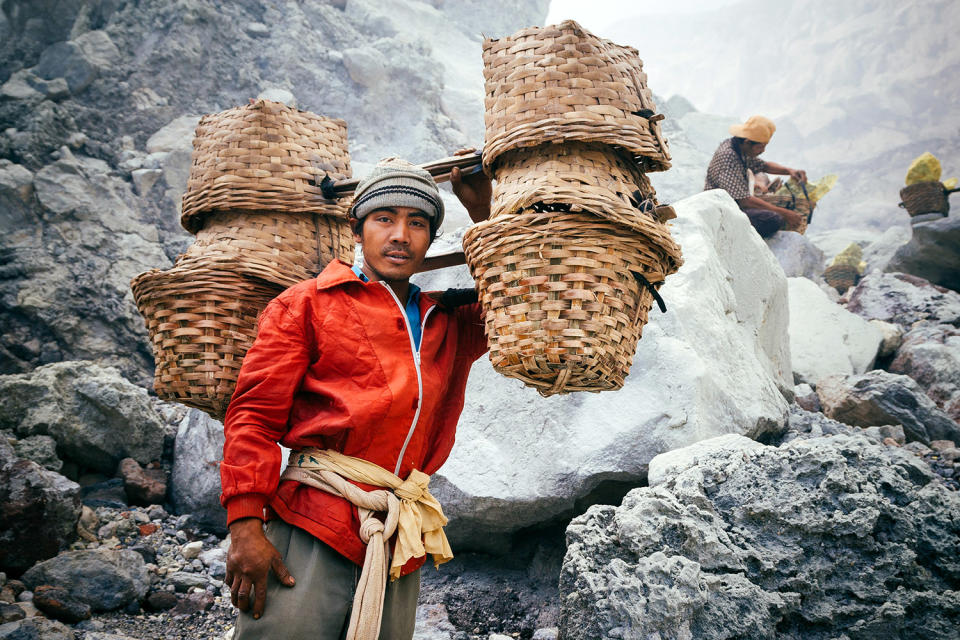 Un trabajador posa para una fotografía con cestas llenas de azufre