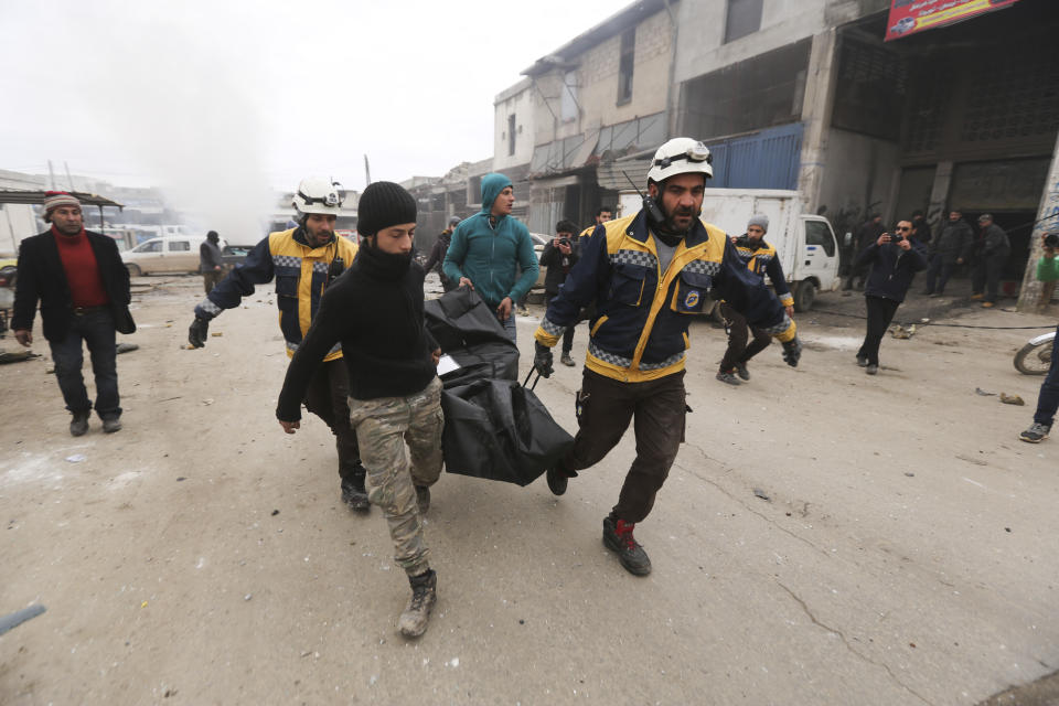 Emergency services carry a body of a person killed in a government airstrike in the city of Idlib, Syria, Tuesday, Feb. 11, 2020. The latest violence in Idlib came as government forces came closer to capturing the last rebel-held part of a strategic highway linking southern and northern Syria, which would bring the road under Syrian President Bashar Assad's full control for the first time since 2012. (AP Photo/Ghaith Alsayed)