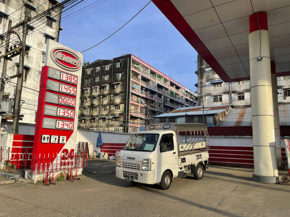 A vehicle is driven near a signboard with fuel prices at a gas station in Botahtaung township in Yangon, Myanmar on Nov. 12, 2021. The military takeover in Myanmar has set its economy back years, if not decades, as political unrest and violence disrupt banking, trade and livelihoods and millions slide deeper into poverty. (AP Photo)