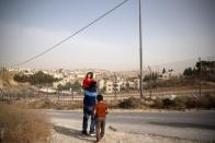 Ismail Odeideh walks with two of his children near an Israeli military barrier in the Palestinian village of Sur Baher, which sits on either side of the barrier in East Jerusalem and the Israeli-occupied West Bank