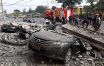 Firefighters stand near damaged vehicles after an earthquake struck Cebu city, in central Philippines October 15, 2013. A strong earthquake measuring 7.2 struck islands popular with tourists in the Philippines on Tuesday killing at least 20 people, some while praying in a centuries-old church, officials said. (REUTERS/Erik De Castro)