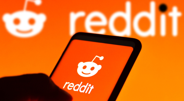 In this photo illustration the Reddit logo seen displayed on a smartphone and on the background. RDDT and the Reddit IPO