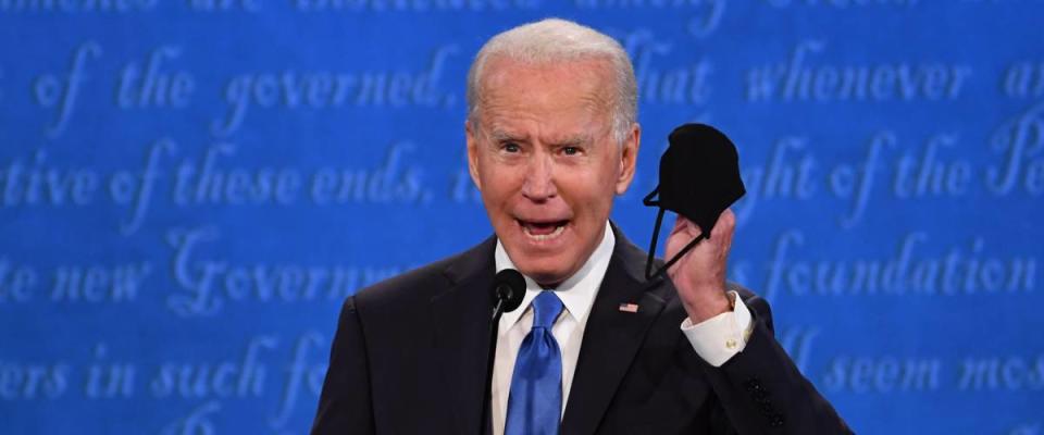 Joe Biden at presidential debate talking into microphone holding his face mask in his hand