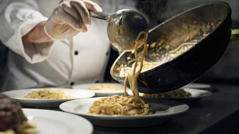 Person plating pasta in restaurant
