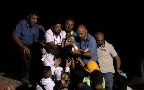 Italian Carabinieri police officer and a doctor carry a child after an earthquake hit the island of Ischia - Credit: REUTERS