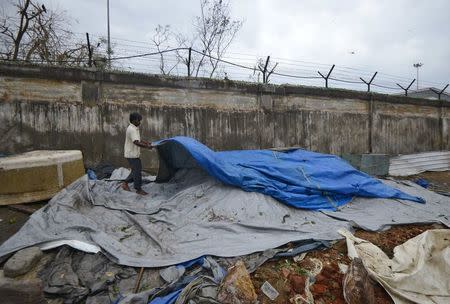 A man fixes a tarpaulin after it was damaged by strong winds caused by Cyclone Hudhud in Visakhapatnam October 13, 2014. REUTERS/R Narendra