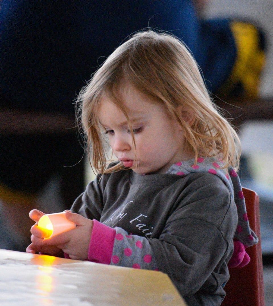 Two-year-old Emily Gackstetter holds an electric candle during a candlelight vigil to remember and honor children lost to miscarriage, including her brother and sister.
