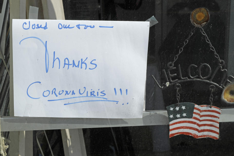 In this May 21, 2020 photo, a sign on a business in Tenino, Wash., says they are closed due to the coronavirus and state stay-at-home restrictions. In an effort to help residents and local merchants alike get through the economic fallout of the coronavirus pandemic, the small town has issued wooden currency for residents to spend at local businesses, decades after it created a similar program during the Great Depression. (AP Photo/Ted S. Warren)