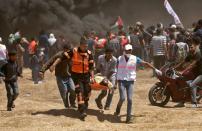 <p>Palestinians carry a demonstrator injured during clashes with Israeli forces near the border between the Gaza Strip and Israel east of Gaza City on May 14, 2018, as Palestinians protested the inauguration of the U.S. Embassy following its controversial move to Jerusalem. (Photo: Mahmud Hams/AFP/Getty Images) </p>