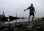 A man throws dead fish back into a polluted river in Ogoniland, Rivers State