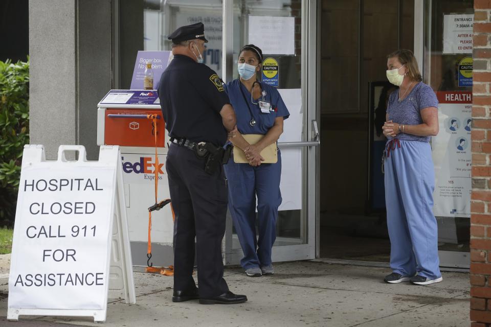 A Norwood, Mass., police officer speaks with medical personnel the day after flooding closed Norwood Hospital in June 2020. About 90 patients had to be evacuated.