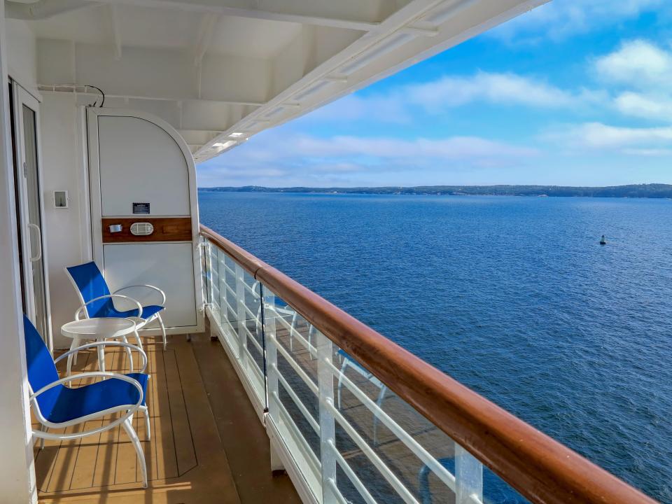 Cruise balcony with blue chairs over looking blue water