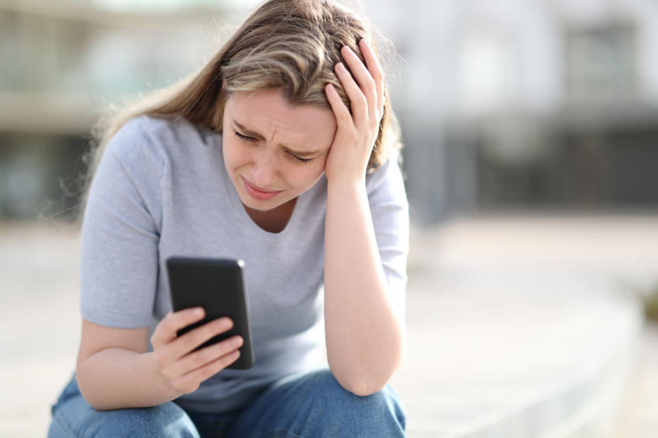 A young girl crying looking at her phone