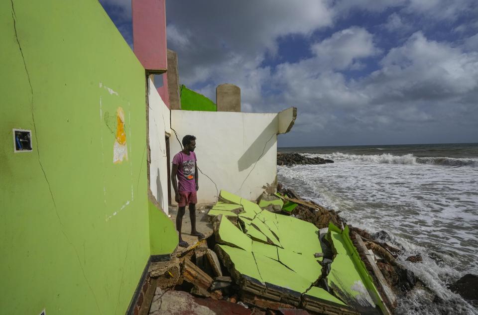 Dilrukshan Kumara looks at the ocean as he stands by the wreck of the remains of his family's home in Iranawila, Sri Lanka, Thursday, June 15, 2023. Much like the hundreds of other fishing hamlets that dot the coastline, the village of Iranawila suffers from coastal erosion. (AP Photo/Eranga Jayawardena)