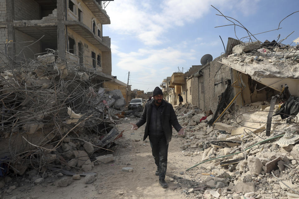 A man walks past collapsed buildings following a devastating earthquake in the town of Jinderis, Aleppo province, Syria, Tuesday, Feb. 14, 2023. The death toll from the earthquakes of Feb. 6, that struck Turkey and northern Syria is still climbing. (AP Photo/Ghaith Alsayed)