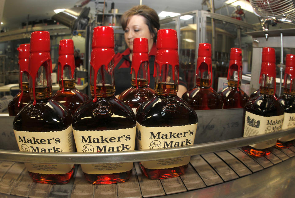 New bottles of Maker's Mark bourbon on the conveyor belt pass by a worker after being hand dipped with their signature red wax, on their way to packaging at the Maker's Mark Distillery plant in Loretto, Kentucky January 23, 2014. (Photo: John Sommers II / Reuters)