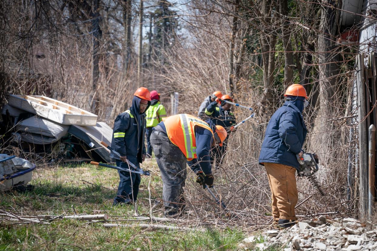 Workers from the Detroit General Services Department work on clearing an alley as city residents and officials celebrate the completion of 3,000 alleys being cleaned of brush, trash and debris. The effort was discussed during a press conference on Thursday, March 28, 2024 in the Russell Woods neighborhood.