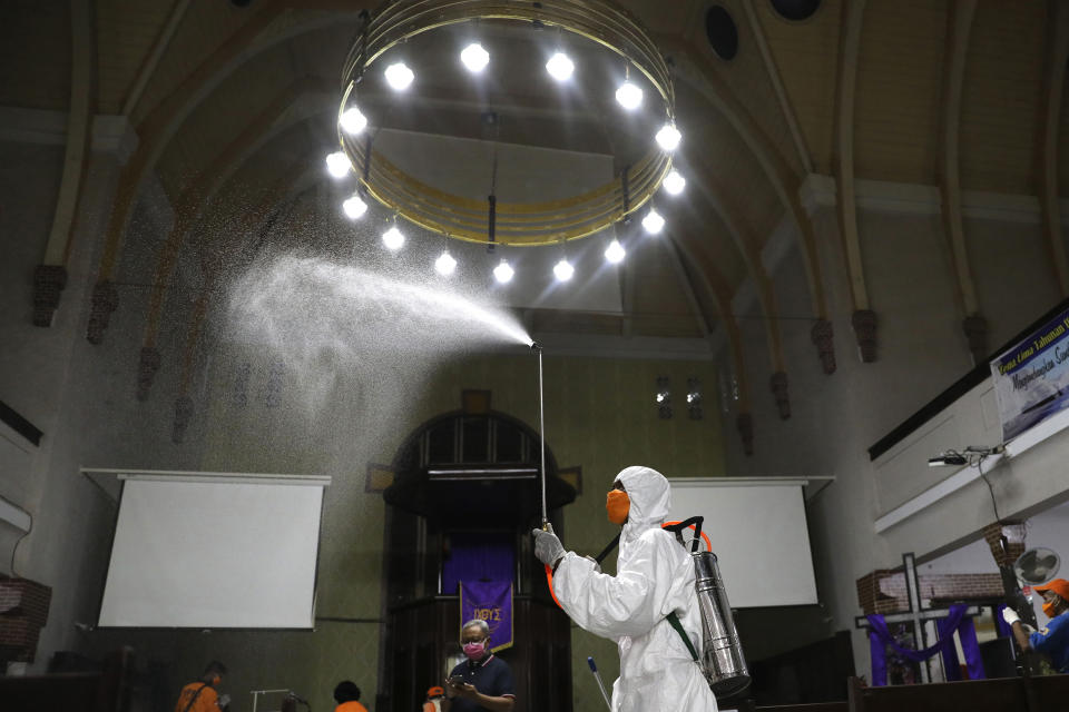 Un operario de la Agencia de Mitigación de Desastres rocía desinfectante dentro de una iglesia por temor a la expansión del nuevo coronavirus, en Surabaya, Java Oriental, Indonesia, el 18 de marzo de 2020. (AP Foto/Trisnadi)