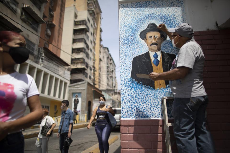 Venezuelan artist Mervin Marmol puts finishing touches on his painting of late Venezuelan Dr. Jose Gregorio Hernandez at the street corner where he died in a car accident in 1919 in La Pastora neighborhood in Caracas, Venezuela, Monday, April 26, 2021. Known as the "doctor of the poor, Hernandez is set to be beatified by the Catholic church, a step towards sainthood, on April 30th. (AP Photo/Ariana Cubillos)