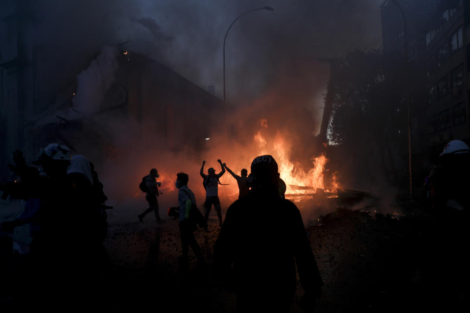 Manifestantes están junto a los escombros de la Parroquia de La Asunción después de que un grupo de personas le prendiera fuego en el primer aniversario del estallido social que sacudió al país en Santiago de Chile el domingo 18 de octubre de 2020. (AP Foto/Esteban Felix)