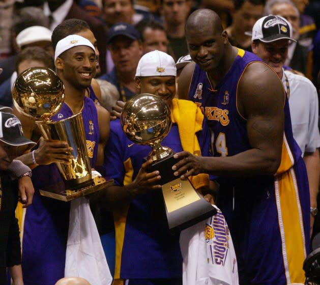 Lakers Kobe Bryant holds up the NBA Trophy as Lindsey Hunter and Shaquille O'Neal hold the MVP Trophy.