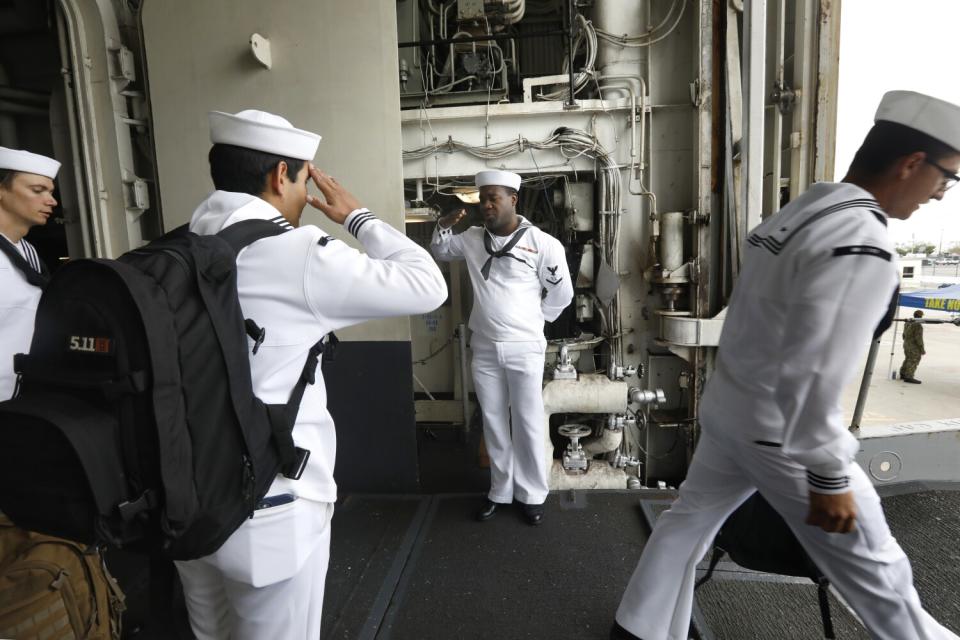 Petty Officer 2nd Class Adrien Michaud, center, salutes as other sailors leave the USS Essex for Fleet Week