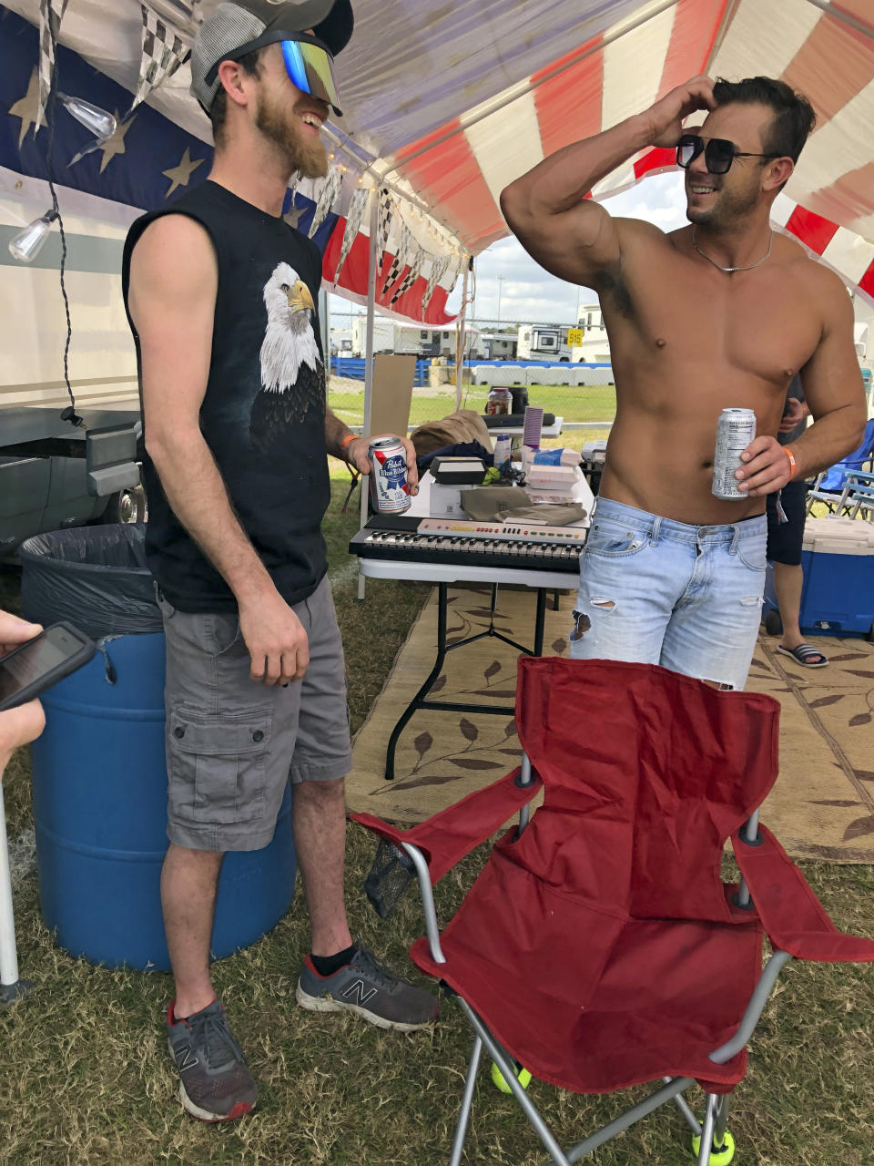 Sam Maxwell, left, and Brandon McCoy talk in the infield at the Daytona International Speedway before a truck race Friday, Feb. 12, 2021, in Daytona Beach, Fla. Daytona is used to shirtless fans partying in the infield. But what about maskless ones? Usually the biggest NASCAR party of the season, the sport will have to figure out how to police up to 30,000 fans who may have little interest in sticking to the pandemic guidelines. How many fans will actually come remains to be seen.(AP Photo/Daniel Gelston)