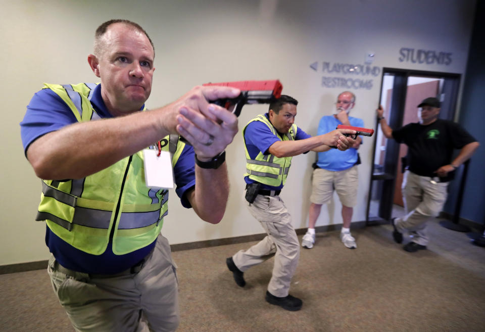 In this July 21, 2019 photo, Police officers David Riggall, left, and Nick Guadarrama, center, demonstrate to students Stephen Hatherley, center rear, and Chris Scott, right rear, how to clear a hallway intersection during a security training session at Fellowship of the Parks campus in Haslet, Texas. While recent mass shootings occurred at a retail store in El Paso, Texas, and a downtown entertainment district in Dayton, Ohio, they were still felt in houses of worship, which haven’t been immune to such attacks. And some churches have started protecting themselves with guns. (AP Photo/Tony Gutierrez)