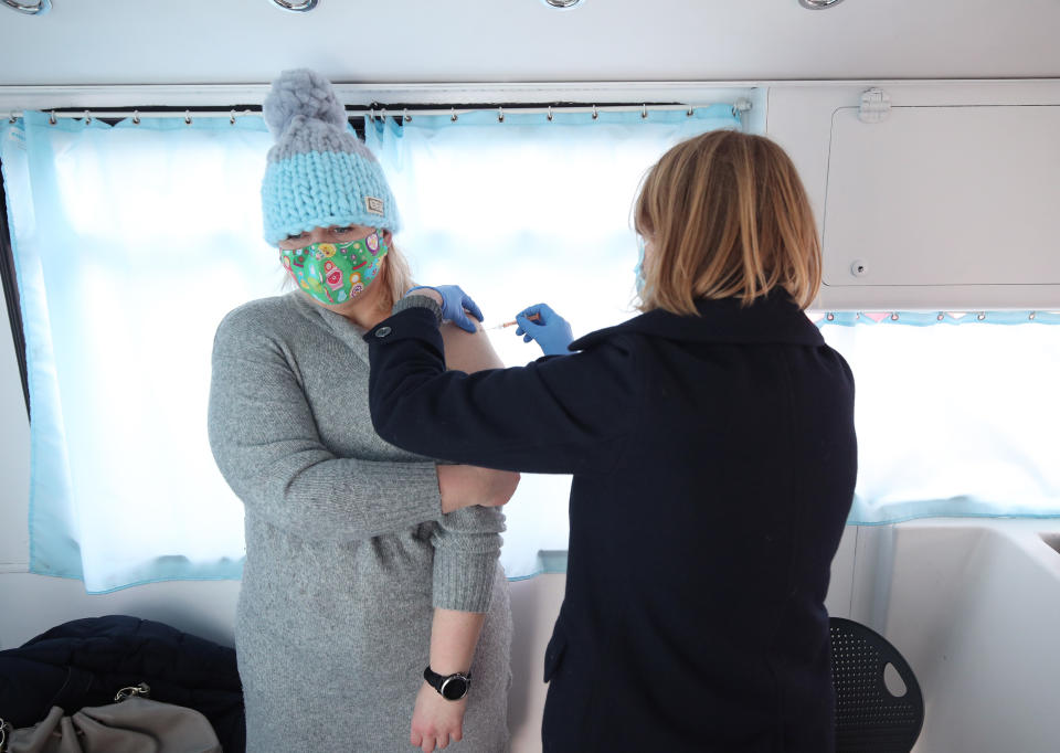 An NHS nurse gives Agata Skorynko, aged 41, a Covid-19 vaccination on board a modified bus, in the car park of the University of Greenwich, London. Picture date: Saturday February 13, 2021. (Photo by Yui Mok/PA Images via Getty Images)